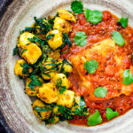 Overhead aloo methi or fenugreek potatoes served with a cod curry.
