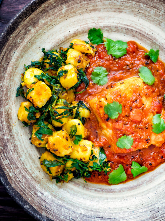 Overhead aloo methi or fenugreek potatoes served with a cod curry.