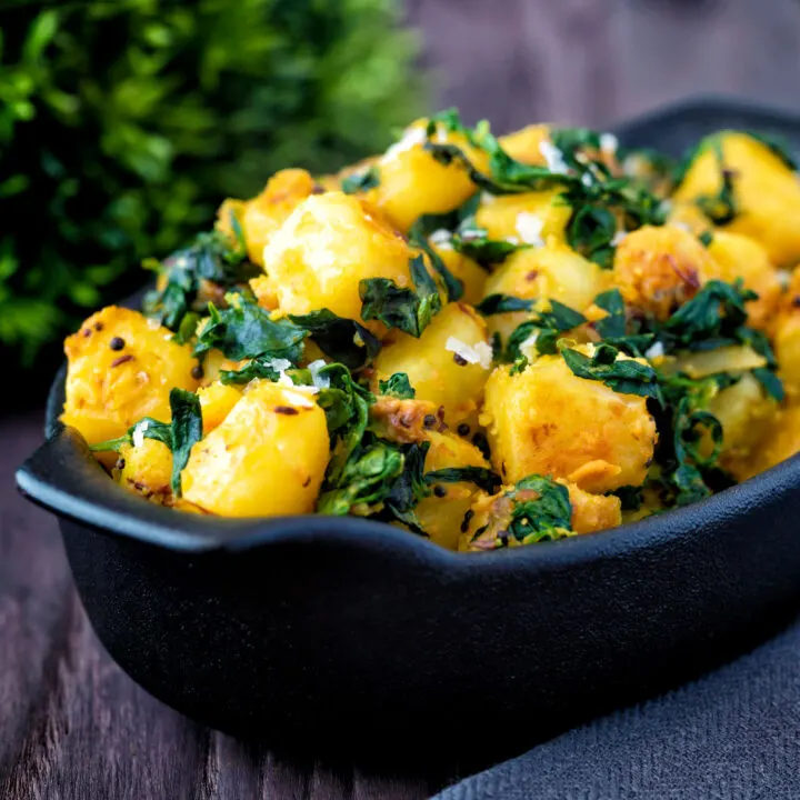 Indian aloo methi or fenugreek potatoes served in a black dish.