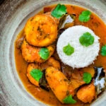 Overhead aloo paneer or chanar dalna served in a bowl with rice and coriander.