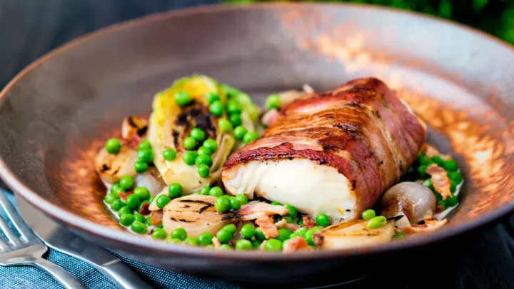 Bacon wrapped cod loin served with petit pois a la Francaise