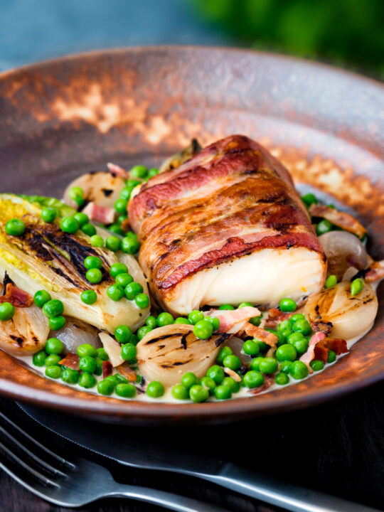 Bacon wrapped cod loin served with French braised peas and lettuce.