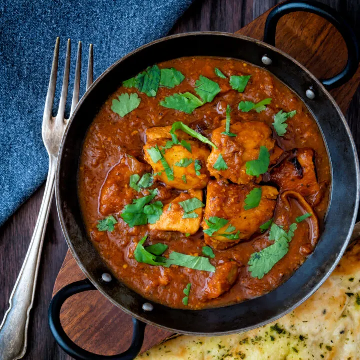 Overhead chicken rogan josh curry with fresh coriander served in an iron kadai.