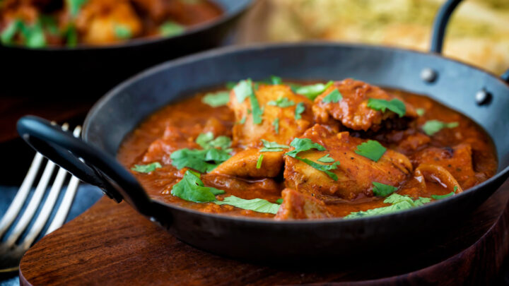 Chicken rogan josh curry with fresh coriander served in an iron kadai.