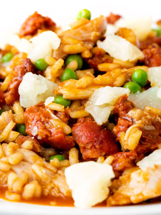 Close up chicken and chorizo risotto with green peas and Manchego cheese.