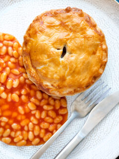 Overhead corned beef and potato pie wrapped in shortcrust pastry served with baked beans.