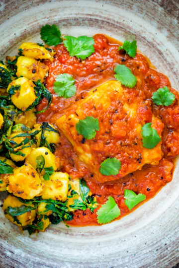 Overhead macher jhol or Bengali fish curry served with aloo methi.