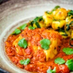 Close up macher jhol or Bengali fish curry served with aloo methi.