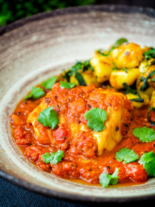 Close up macher jhol or Bengali fish curry served with aloo methi.