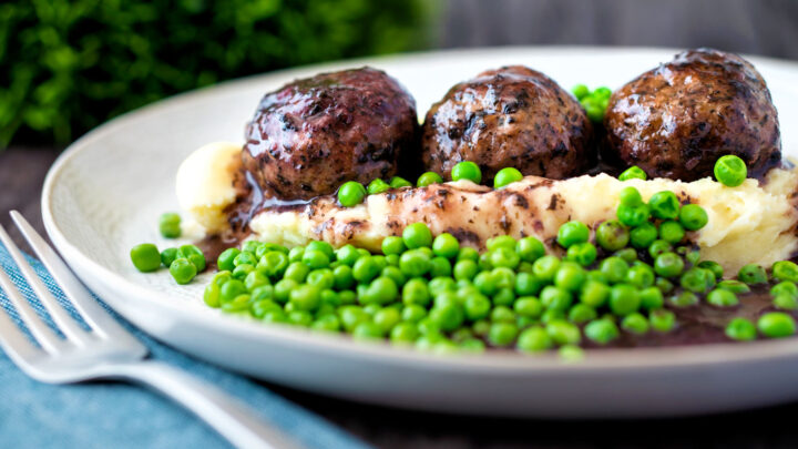 Minted lamb meatball with red wine gravy served with mashed potato and green peas.