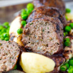 Cut open minted lamb meatball with red wine gravy served with mashed potato and peas.