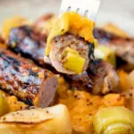 A piece of sausage from a sausage and apple casserole served with swede and carrot mash.