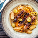 Overhead sausage and apple casserole with leeks and a mustard and cider sauce.