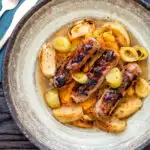 Overhead sausage and apple casserole with leeks and a mustard and cider sauce.