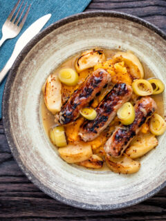 Overhead sausage and apple casserole with leeks and a mustard and cider sauce.