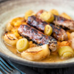 Sausage and apple casserole with leeks and a mustard and cider sauce featuring a title overlay.