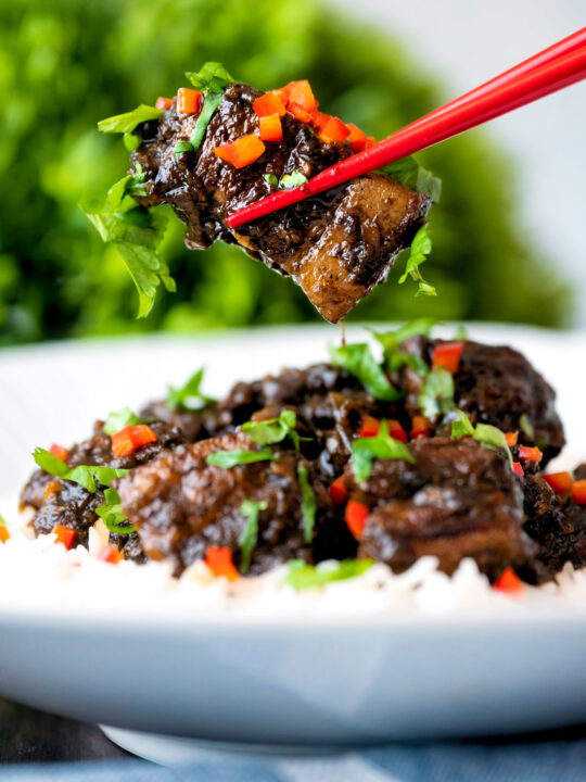 Babi chin Indonesian soy sauce braised pork belly being eaten with chop sticks.