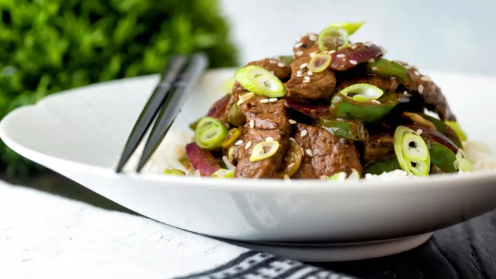 Black pepper beef stir fry with green pepper, red onion and spring onion.