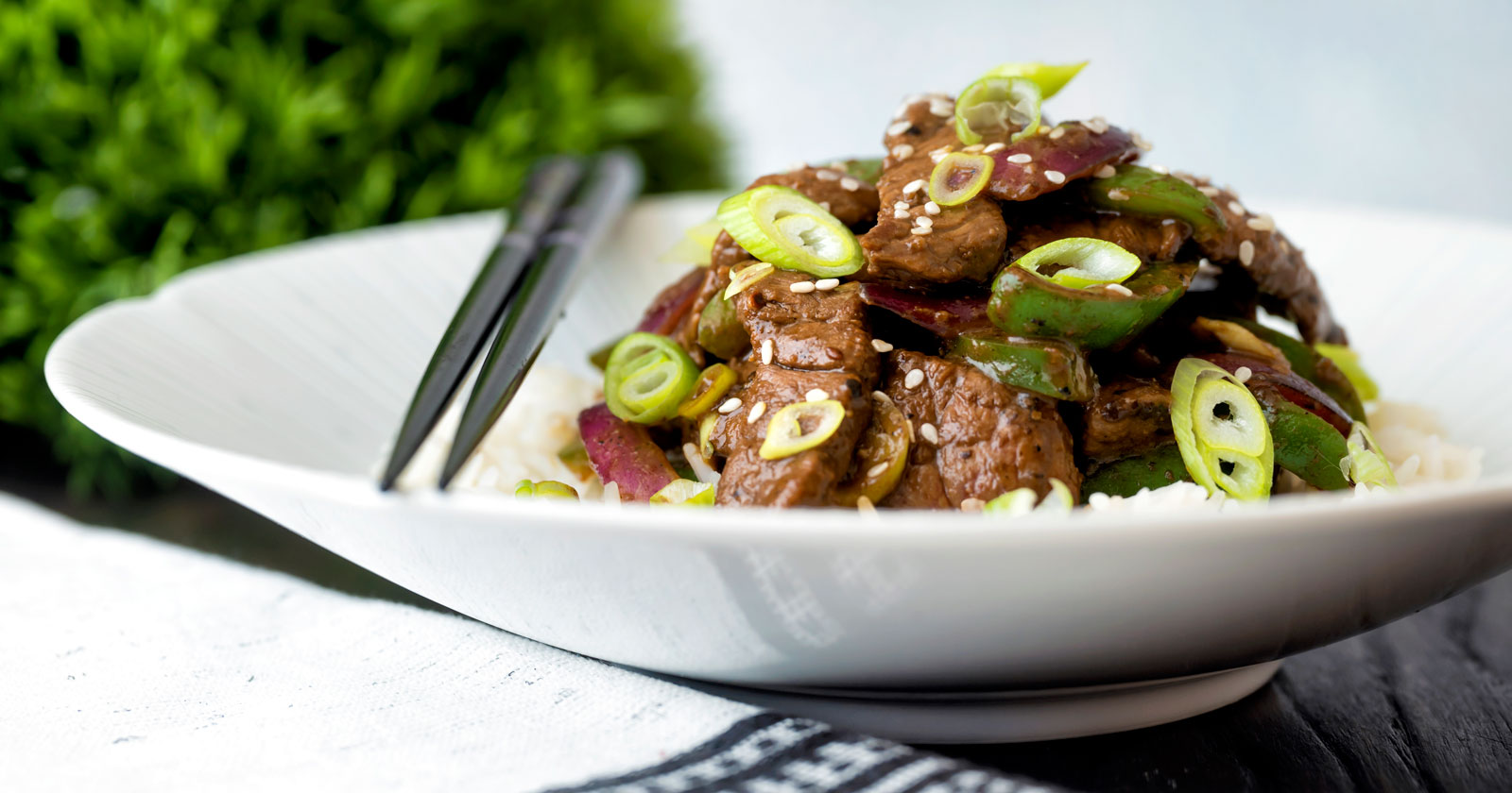 Black pepper beef stir fry with green pepper, red onion and spring onion.