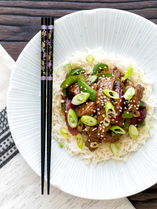 Overhead black pepper beef stir fry with green pepper and red onion.