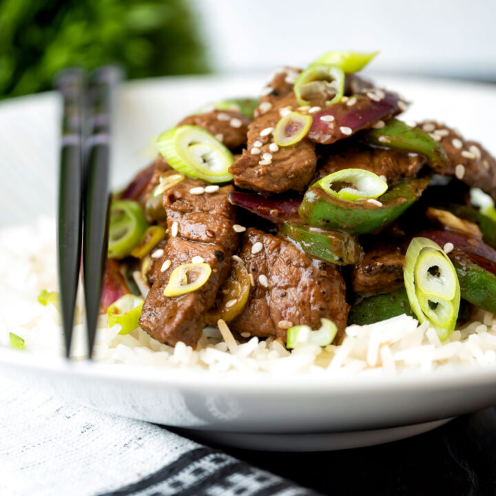 Black pepper beef stir fry with green pepper, red onion and spring onion.