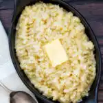 Overhead bowl of buttery celeriac mash served with an extra knob of butter.
