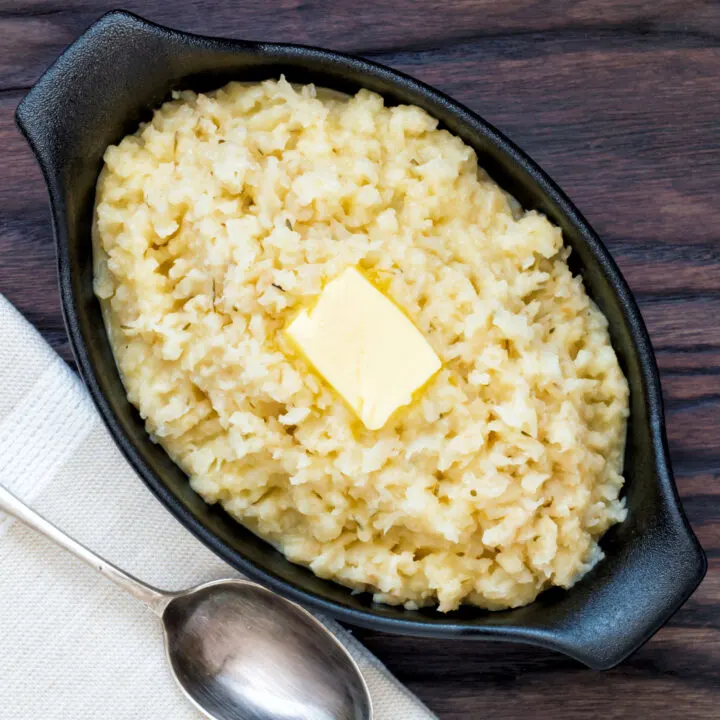 Overhead bowl of celeriac mash served with a knob of butter.