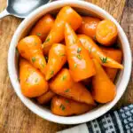 Overhead brown sugar and butter glazed Chantenay carrots with fresh thyme featuring a title ovelay.
