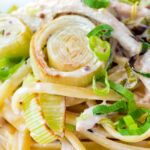 Close up chicken and leek pasta with linguini and shredded spring onions.
