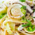 Close up chicken and leek pasta with linguini and shredded spring onions.