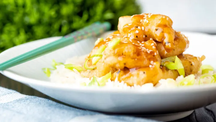 Chinese takeaway style crispy lemon chicken served with rice and spring onions.