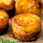 Fondant potatoes poached in butter and stock with a sprig of thyme featuring a title overlay.