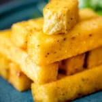 Stack of fried polenta chips with one broken in half to show texture.