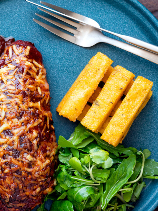 Overhead stack of fried polenta chips with green salad.