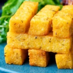 Stack of fried polenta chips with green salad.