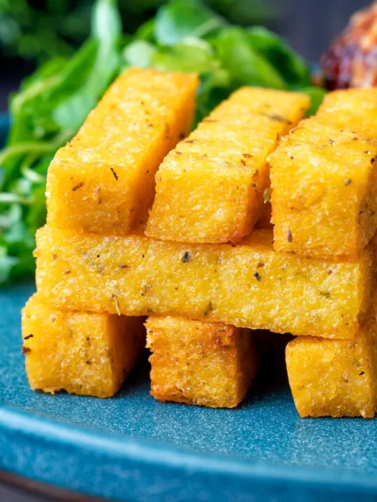 Stack of fried polenta chips with green salad.