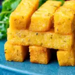 Stack of fried polenta chips with green salad featuring a title overlay.