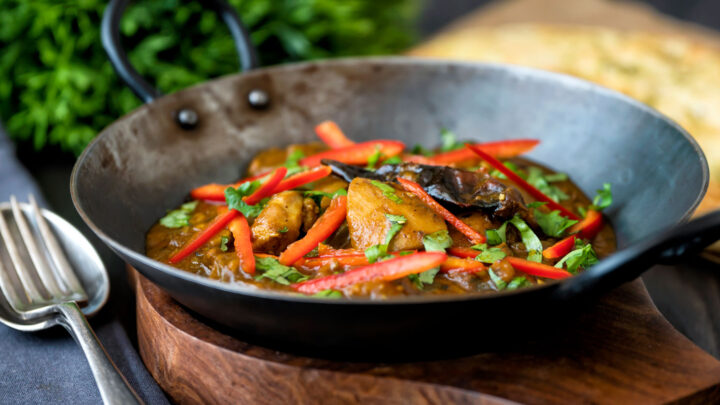 Garlic chilli chicken curry served with fresh chilli and coriander in an iron karai.