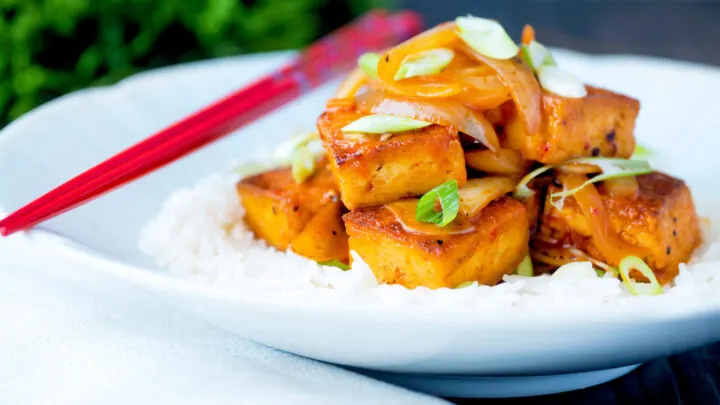 Vegan Korean gochujang tofu stew with kimchi served with white rice and spring onions.