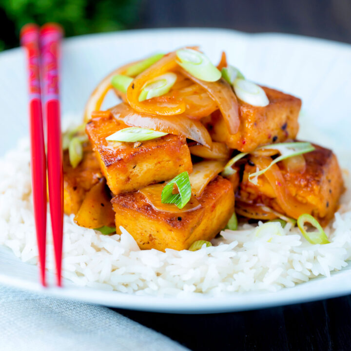 Vegan Korean gochujang tofu stew with kimchi served with white rice and spring onions.