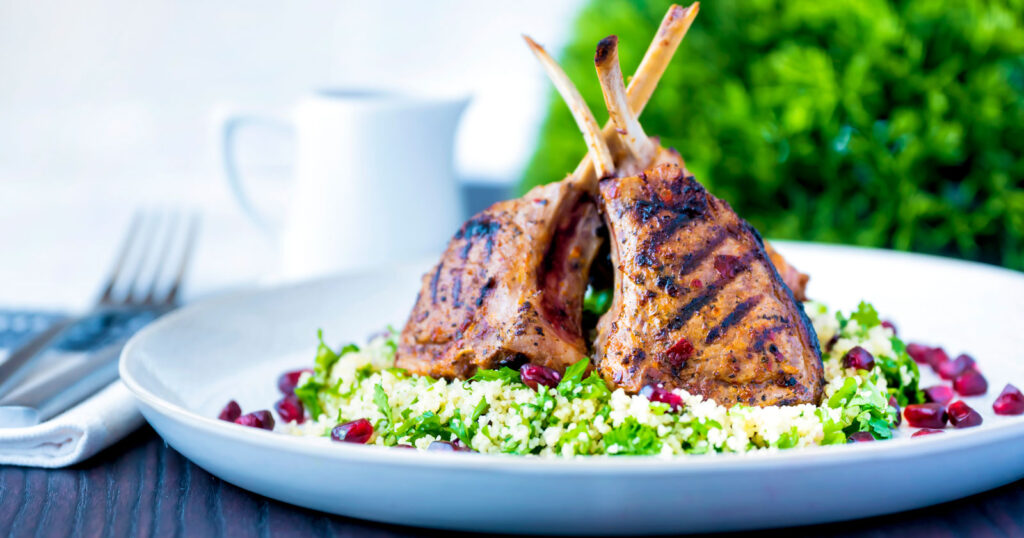 Harissa lamb chops with herby buttered couscous and pomegranate arils.