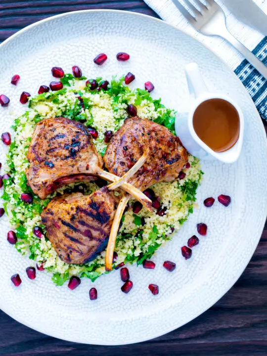 Overhead harissa lamb cutlets served on herby buttered couscous with a spicy sauce.