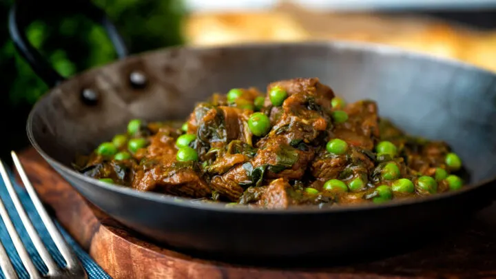 Methi gosht (beef and fenugreek) curry with peas served in an iron karahi.