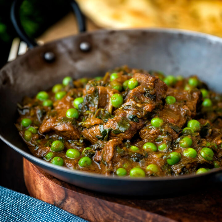 Methi gosht (beef and fenugreek) curry with peas served in an iron karahi.