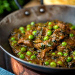 Close up methi gosht (beef and fenugreek) curry with peas served in an iron karai featuring a title overlay.
