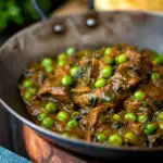 Close up methi gosht (beef and fenugreek) curry with peas served in an iron karai featuring a title overlay.