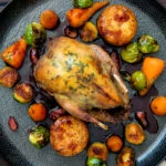 Overhead roast partridge served with red currant sauce and fondant potatoes.