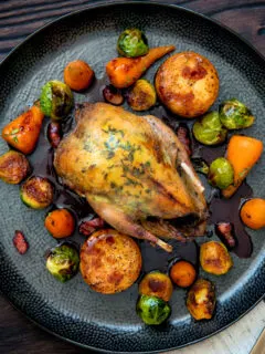 Overhead roast partridge served with red currant sauce and fondant potatoes.