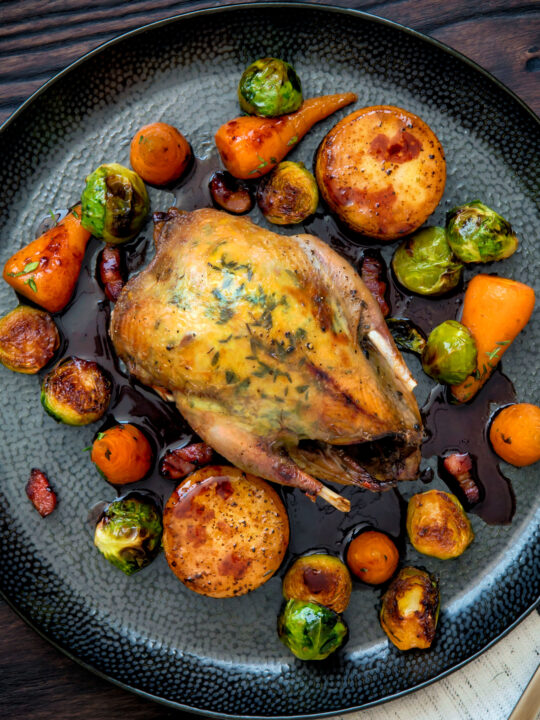 Overhead roast partridge served with red currant sauce and fondant potatoes.