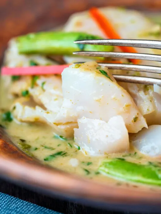 Close up Thai green fish curry showing big flakes of perfectly cooked cod.